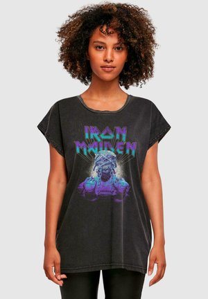 Sort oversized t-shirt med korte ærmer, prydet med et livligt lila- og grønt Iron Maiden grafik af en skeletfigur.