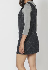 Gray long-sleeve top beneath a navy blue plaid dress. The dress has a fitted bodice, slight A-line shape, and textured fabric.