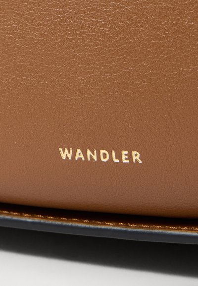 Barna bőr, textúrált felülettel, amelyen a "WANDLER" márkaneve arany színben van emelve. Az éle kontrasztos sötétkék árnyalatú.