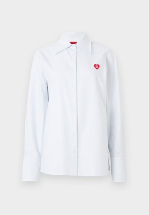 Valge triibuline summeerusärgi sinisest puuvillasest tumedamast sinisest, klassikalise kraega ja väikese punase südame logoga rinnal. Pikkade varrukatega ja mansettidega.