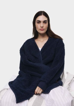Accappatoio in fleece di colore blu navy, oversize, con tessuto testurizzato, maniche lunghe e apertura frontale. Design morbido e accogliente, adatto per il relax.