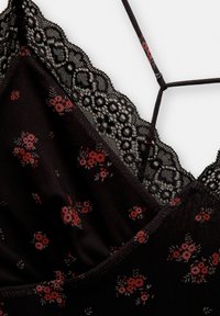Camisole en tissu noir avec un motif floral en rouge et rose, bordure en dentelle au niveau de l'encolure, et bretelles croisées. Texture lisse.