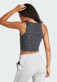 Μαύρο crop τοπ με λεοπάρ σχέδιο, διαθέτει στρογγυλή λαιμόκοψη και χωρίς μανίκια, συνδυασμένο με ανοιχτό γκρι φόρμες.