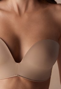 Nude, kleefvrije strapless bh met een gladde, gevormde pasvorm en V-halslijn. Gemaakt van zacht, rekbaar materiaal met subtiele naaddetails.