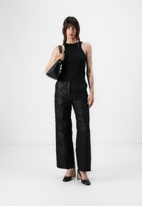 Black sleeveless top with a fitted design, paired with wide-leg black pants featuring a floral texture. Accessories include a small black bag.