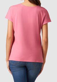 Tričko s krátkým rukávem a kulatým výstřihem v světle růžové barvě, vyrobené z měkké látky. Má uvolněný střih, jednoduchý design a jemnou strukturu.