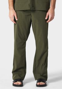 Pantalones livianos de color verde oliva con un diseño de pierna recta. Fabricados con una tela suave, con una textura lisa y detalles de costura mínimos.