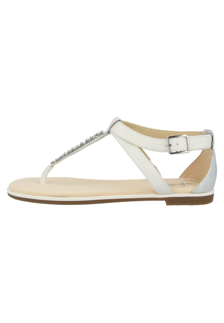 Sandali piatti bianchi con design a T, caratterizzati da un accento argento e dettagli decorativi di perline lungo la cinghia. Soletta soffice e imbottita.