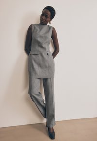Sivý strihaný dvojdielny oblek s topom bez rukávov a nohavicami rovného strihu. Hladká textúra s jemnými vzorovými detailmi.