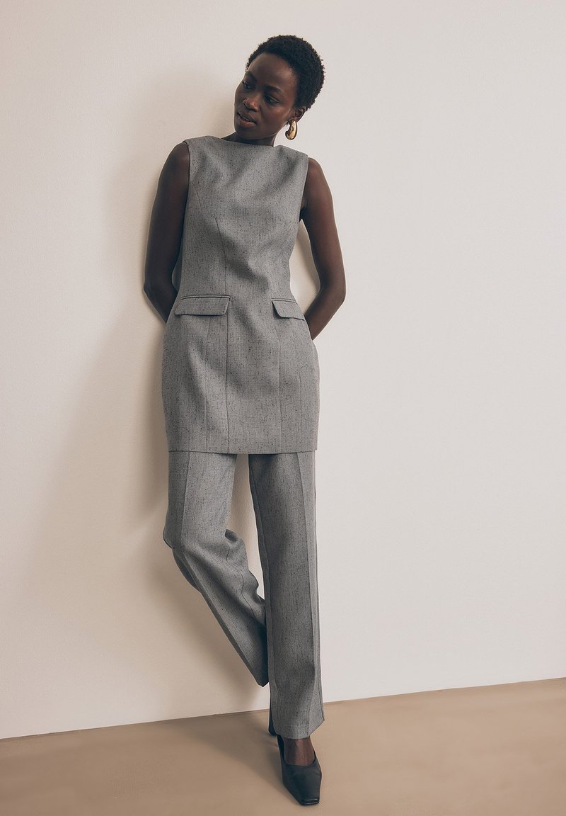 Sivý strihaný dvojdielny oblek s topom bez rukávov a nohavicami rovného strihu. Hladká textúra s jemnými vzorovými detailmi.