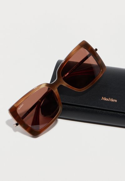 Καφέ υπερμεγέθη τετράγωνα γυαλιά ηλίου που ακουμπούν σε μαύρη σκληρή θήκη με το λογότυπο Max Mara πάνω σε λευκό φόντο.