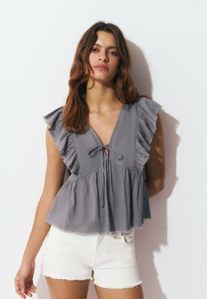 Top gris de manga corta con escote en V, adornos de volantes en las mangas, un lazo en el cuello y un diseño fluido y recogido.