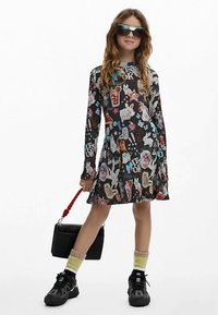 Vestito nero a maniche lunghe con grafiche colorate di animali e cibo, con orlo svasato. Abbinato a sneakers nere, calzini al ginocchio e una borsa.