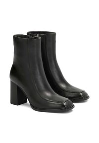 Botas de cuero negro hasta el tobillo con punta cuadrada, cremalleras laterales y tacones cuadrados, expuestas sobre un fondo blanco.