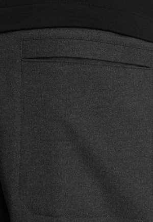 Tamsiai pilkos kelnės su lygiu paviršiumi, turinčios stačiakampį užpakalinį kišenę. Audinys atrodo minkštas su subtiliu šviesiai pilkų drožlių raštu.