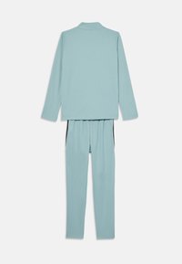 Ensemble de survêtement bleu clair comprenant un haut à manches longues avec col et un pantalon assorti. Les deux pièces présentent une texture lisse et minimale.