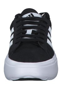 Čierne športové topánky s bielym dizajnom troch pruhov, so štruktúrovaným zvrškom a hrubou bielou podrážkou. Šnúrky prechádzajú očkami na vrchu.