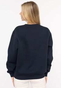Marineblaue Rundhals sweatshirt aus weichem Stoff; mit gerippten Bündchen und Saum, lässiger Schnitt und ohne sichtbare Logos oder Muster.