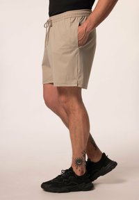 Beige zwemshorts van lichtgewicht materiaal, met een elastische tailleband met koord en zijzakken.