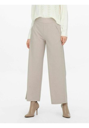Beige broek met wijde pijpen en zijzakken, gedragen met taupekleurige laarsjes met spitse neus en een crème gebreide trui.