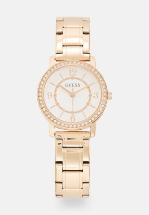 Orologio Guess dorato con cassa rotonda, quadrante bianco, accenti di cristallo e bracciale a maglie. Presenta audaci numeri arabi e marker delle ore.