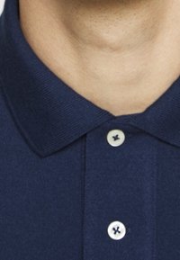 Mörkblå pikétröja med ribbad krage, utrustad med tre knappar i kontrasterande ljus färg och en slät, texturerad tyg.