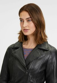 Zwarte leren motorjack met een geknikt kraag, asymmetrische ritssluiting en subtiele stikdetails. Ideaal voor casual wear.