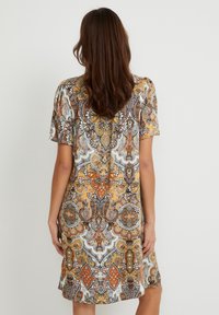 Kortärmad klänning med ett intrikat paisleymönster i orange, brunt och vitt. Tillverkad av mjukt tyg, har en lös passform och knälång fåll.