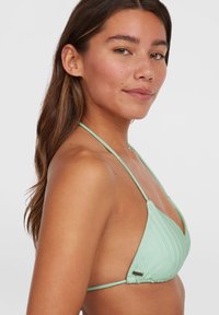 Mintgrønn bikini-topp med teksturert stoff, trekantet form og tynne justerbare stropper. Inkluderer liten metallisk logo-detalj.