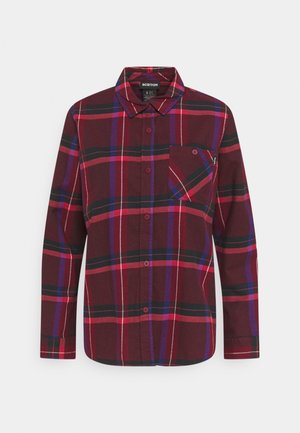 Camisa de manga larga con botones, con un patrón de cuadros en rojo, negro, morado y rosa, y un bolsillo en el pecho, sobre un fondo blanco.