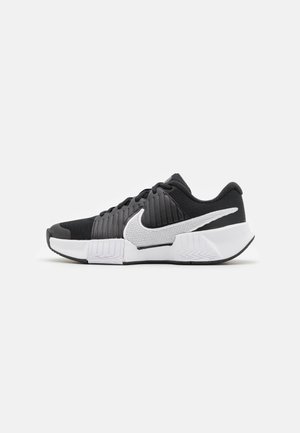 Svart-hvite joggesko med teksturert overdel, fremtredende Nike-svusk og kontrasterende såledesign for bedre grep og stabilitet.