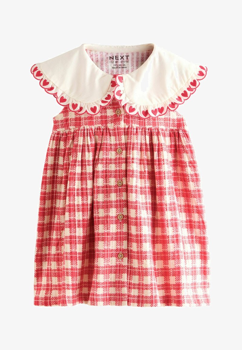 Czerwona i biała sukienka w kratę z białym kołnierzykiem z konturami serc, guzikami z przodu i elastycznym pasem. Wykonana z bawełny.