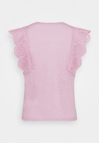 Pink t-shirt featuring scalloped lace sleeves with circular cutouts. Soft fabric with a relaxed fit and rounded neckline.