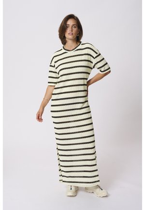 Striped knit dress in cream with black horizontal stripes, featuring a loose fit, short sleeves, side slits, and worn with white sneakers.