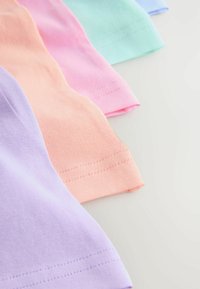 Štyri zložené kusy bavlnenej tkaniny v pastelovej fialovej, broskyňovej, ružovej a mätovo zelenej farbe usporiadané diagonálne na svetlom povrchu.