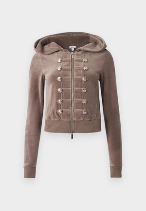 Καφέ βελούδινο φούτερ με φερμουάρ μπροστά, διακοσμημένο με κάθετες σειρές ασημένιων κουμπιών και ραβδωτές μανσέτες και στρίφωμα.