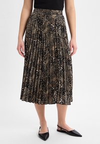 Geplooide midi rok in zwart en bruin dierenprint, voorzien van een elastische tailleband en een vloeiende ontwerp. Gecombineerd met zwarte puntige schoenen.