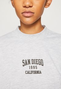 Gray cotton sweatshirt with a crewneck, featuring a dark brown print saying "SAN DIEGO 1995 CALIFORNIA" at the center.