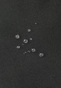 Gocce d'acqua su un tessuto nero testurizzato, che mette in evidenza un materiale durevole e resistente all'acqua. Dettagli riflettenti evidenziano la superficie.