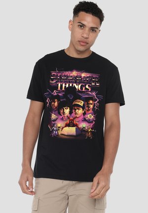 Black short-sleeve t-shirt featuring a colorful "Stranger Things" graphic with characters, dice, and dramatic lightning accents.