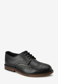 Zwarte leren dress shoe met brogue-details, voorzien van een ronde neus, vetersluiting en een bruine geprofileerde buitenzool.