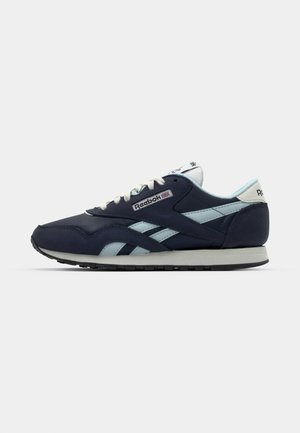 Navy and light blue sneakers with a textile and suede upper, featuring Reebok branding and a rubber sole with a textured grip pattern.