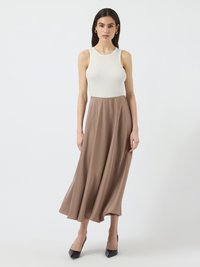 Ribbed white tank top paired with a flowing brown midi skirt. The outfit features a smooth texture and black pointed heels for contrast.