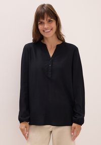 Schwarze Bluse mit langen Ärmeln und Stehkragen, Knopfverschluss mit drei Knöpfen und gerafften Manschetten, aus glattem Stoff mit leichtem Glanz.