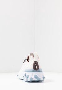 Sko med ett lätt, mjukt rosa tygöverdrag, blå accenter och en strukturerad sula med cirkulära noder för grepp och flexibilitet.