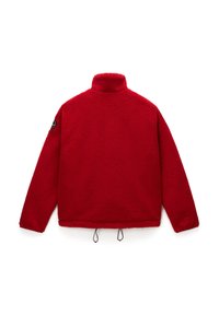 Jachetă roșie din fleece cu guler înalt, mâneci lungi, șnururi ajustabile la tiv și un patch circular pe mâneca stângă.