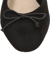 Bailarinas de ante negro con punta redonda, que presentan un pequeño detalle de lazo y un forro interior suave. Diseño simple y uniforme.