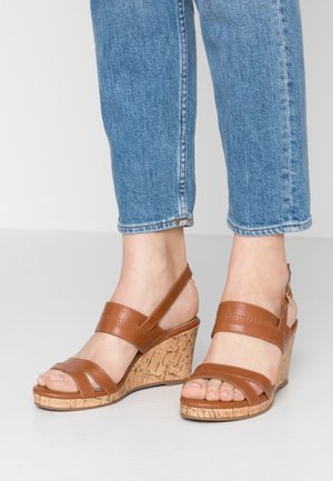 Brune læder kilehøjhælede sandaler med hæl i korktekstur. To brede remme over foden og en justerbar rem bagpå.