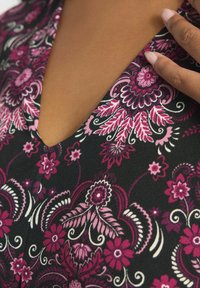 Czarna tkanina z misternym kwiatowym wzorem w różowym i białym, z dekoltem w serek i szczegółowymi zdobieniami na linii dekoltu.