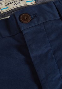 Navyblaue Stretch-Chinos mit glatter Textur, slim Fit und einem Vierknopfverschluss am Bund mit einem hellbraunen Knopf.